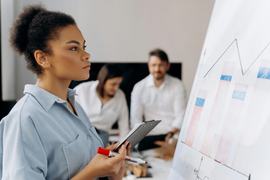 Focused businesswoman analyzing data on a whiteboard during a team meeting.
